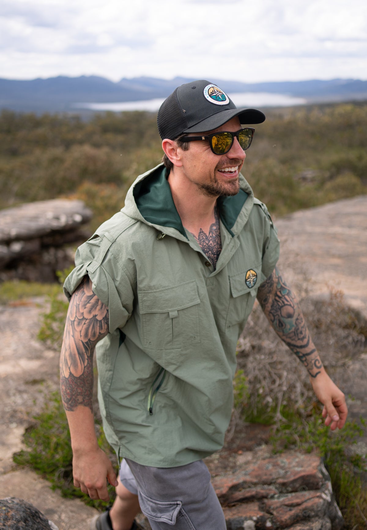 Man wearing a green jacket and cap with a scenic background